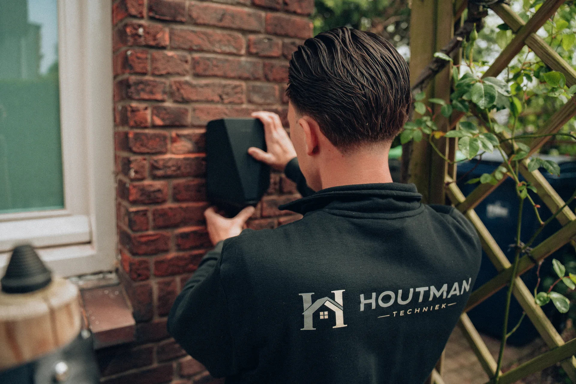 Houtman Techniek monteur plaatst laadpaal aan bakstenen muur