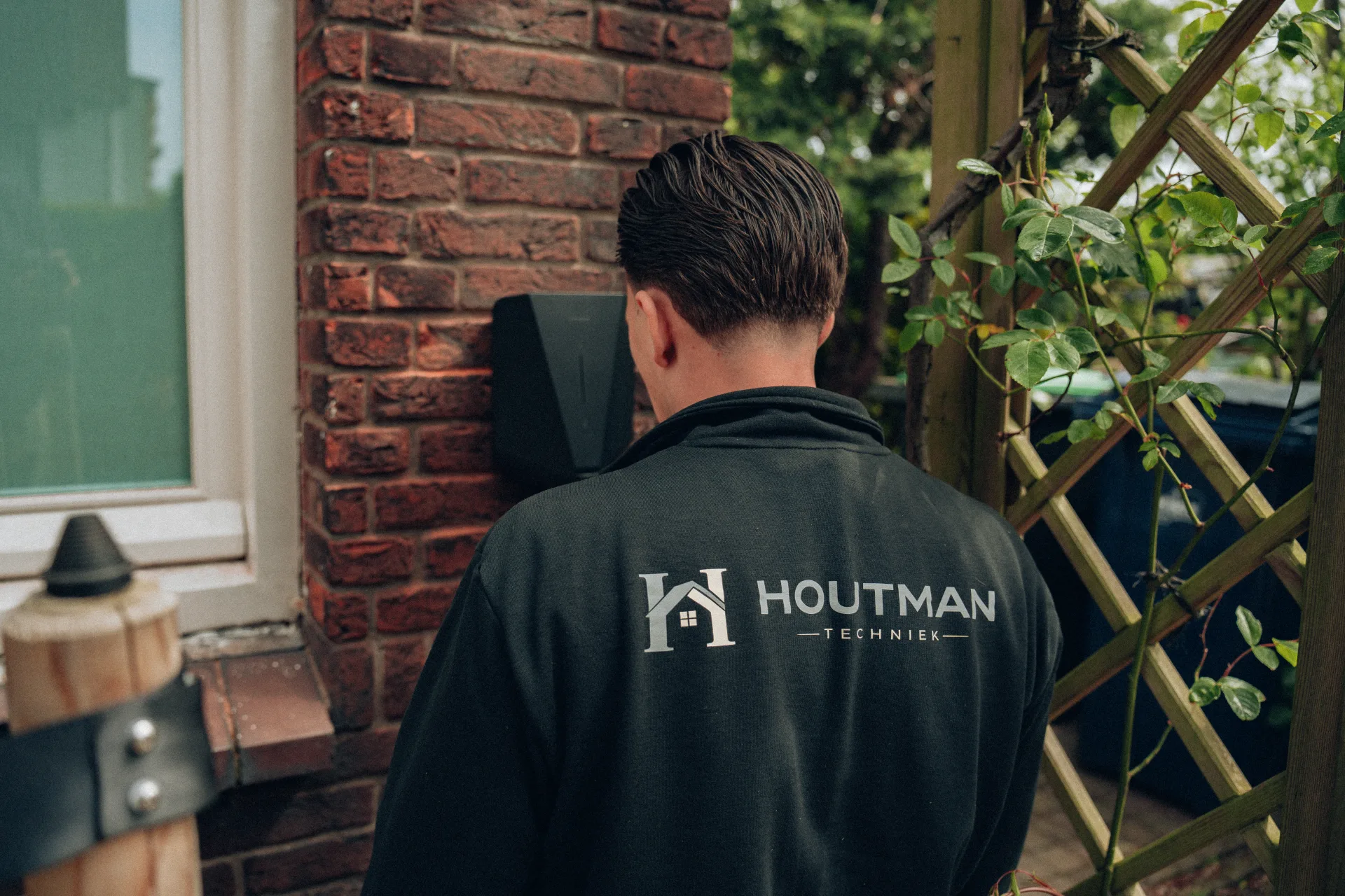 Monteur met Houtman logo monteert laadpaal bij woning