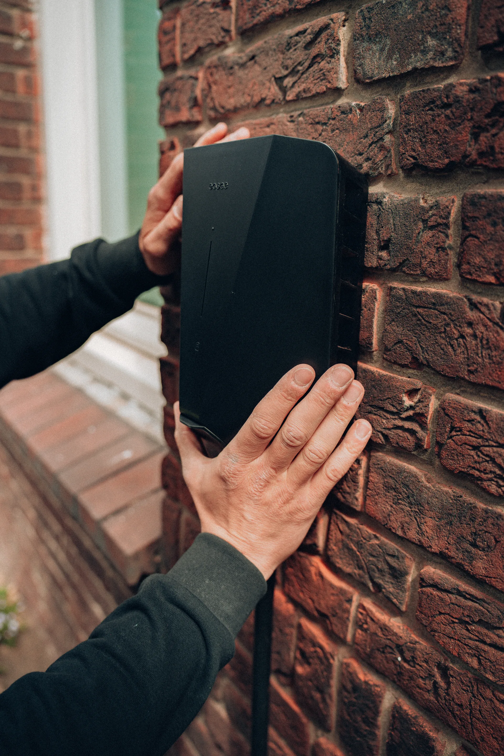 Handen monteren laadpaal aan woningmuur