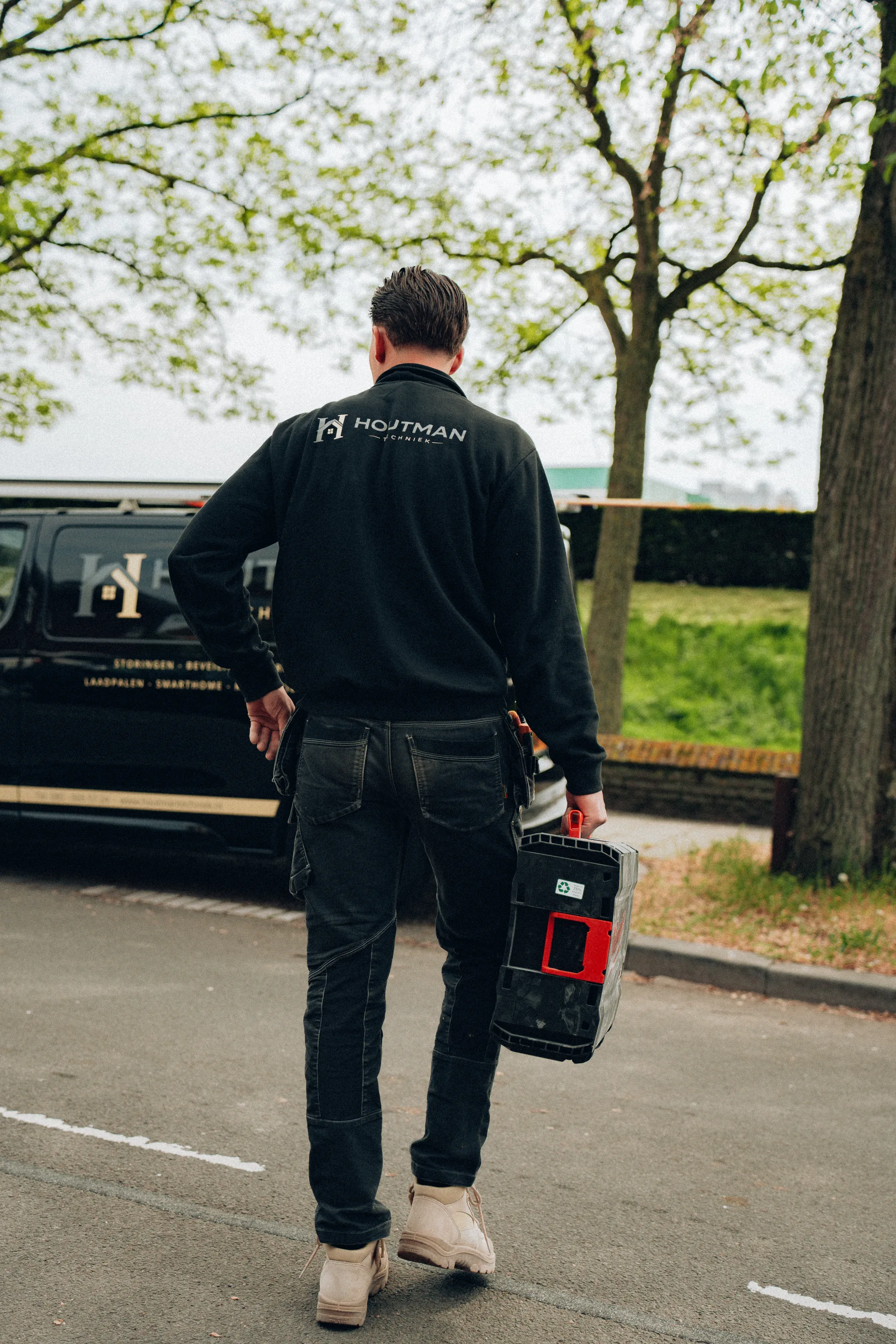 Monteur loopt met gereedschapskoffer naar werkbus