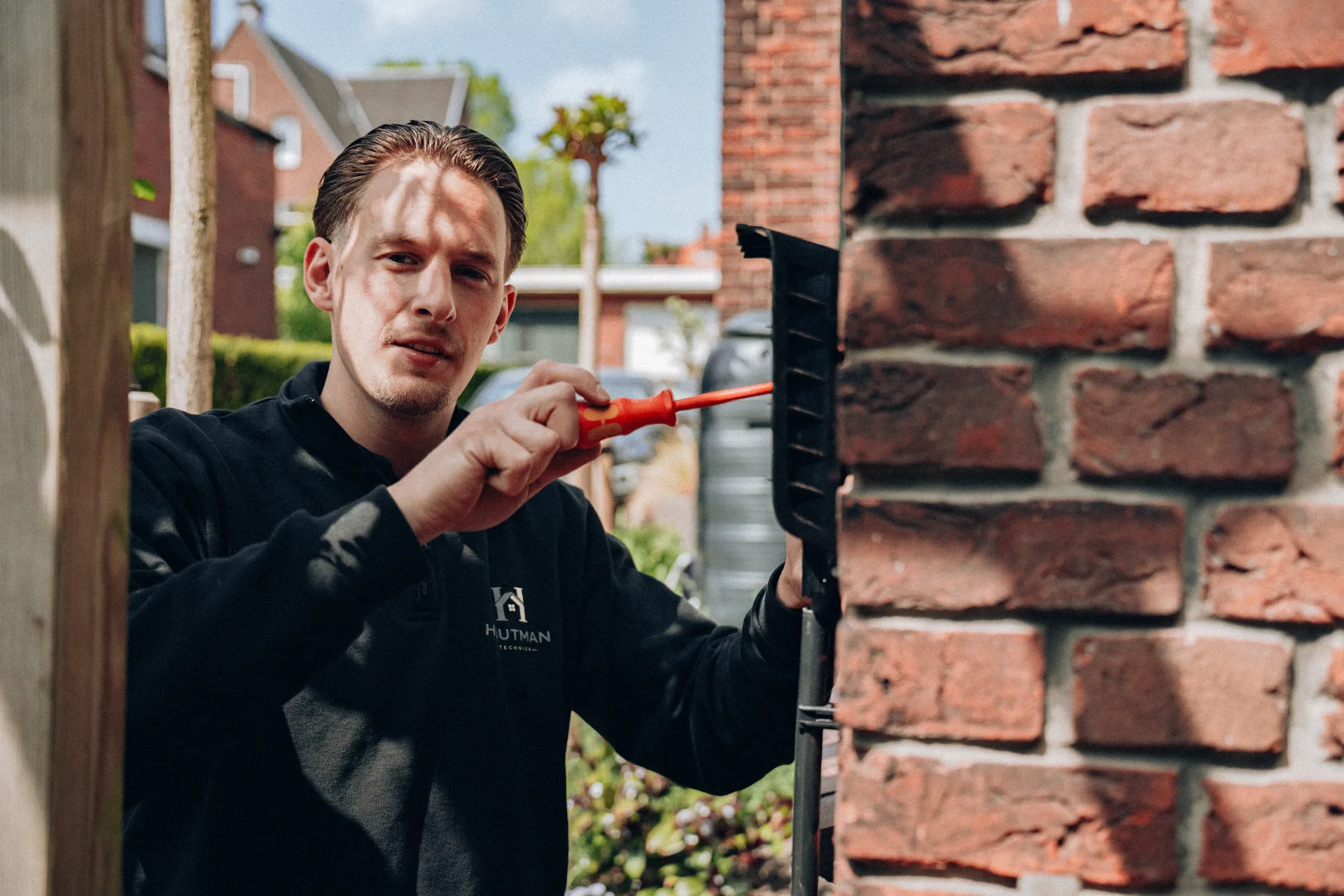 Monteur werkt met schroevendraaier aan installatie bij woning